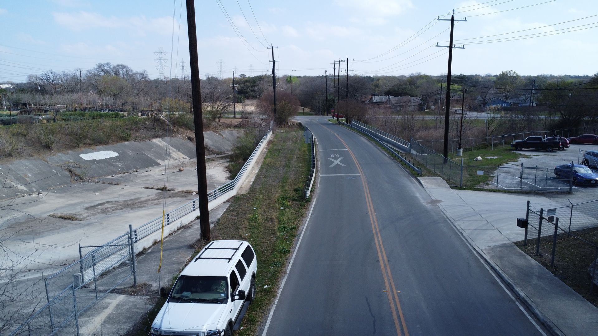 Concrete bridge over a dry riverbed. Grassy banks lead up to the structure.