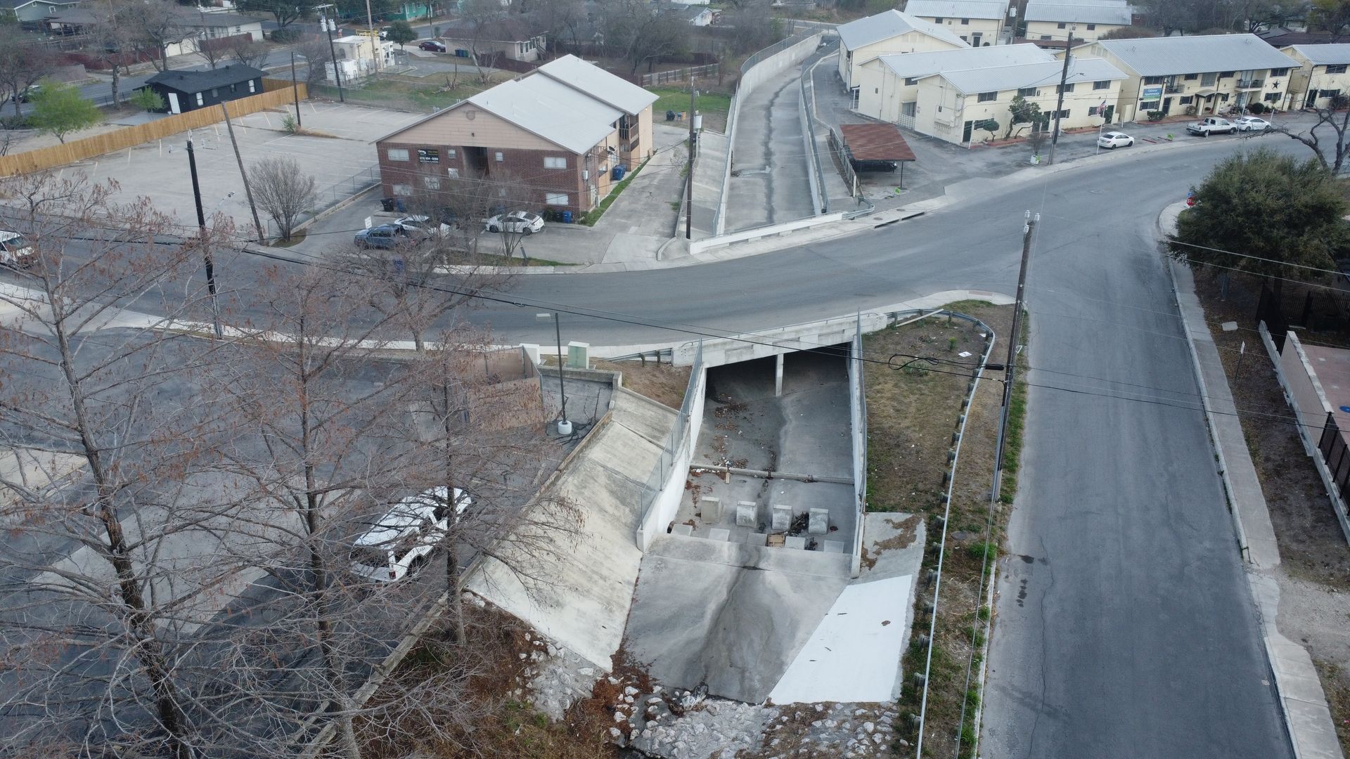 Concrete drainage canal under a bridge, with steps and barriers visible.