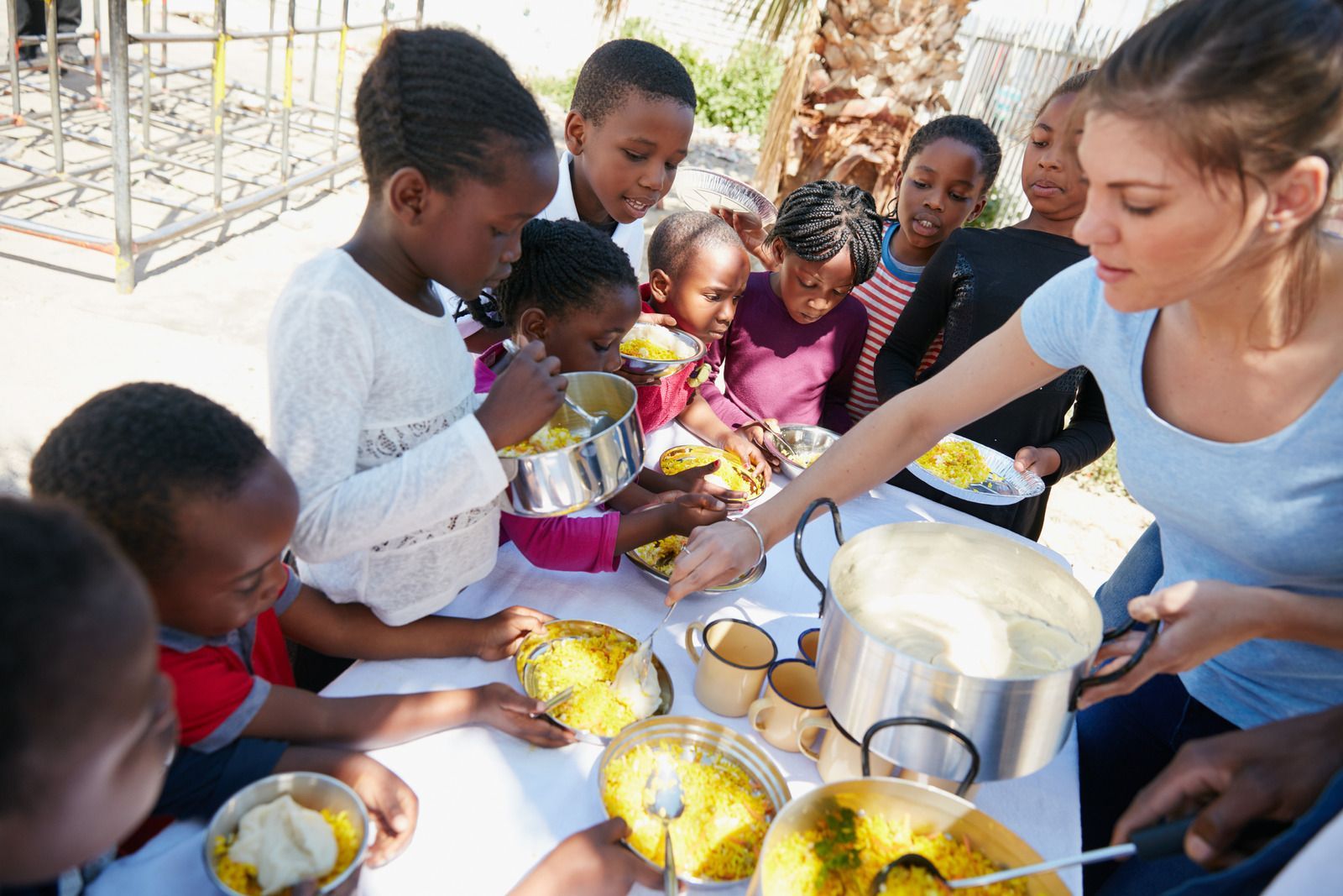 A woman is serving food to a group of children at a table.