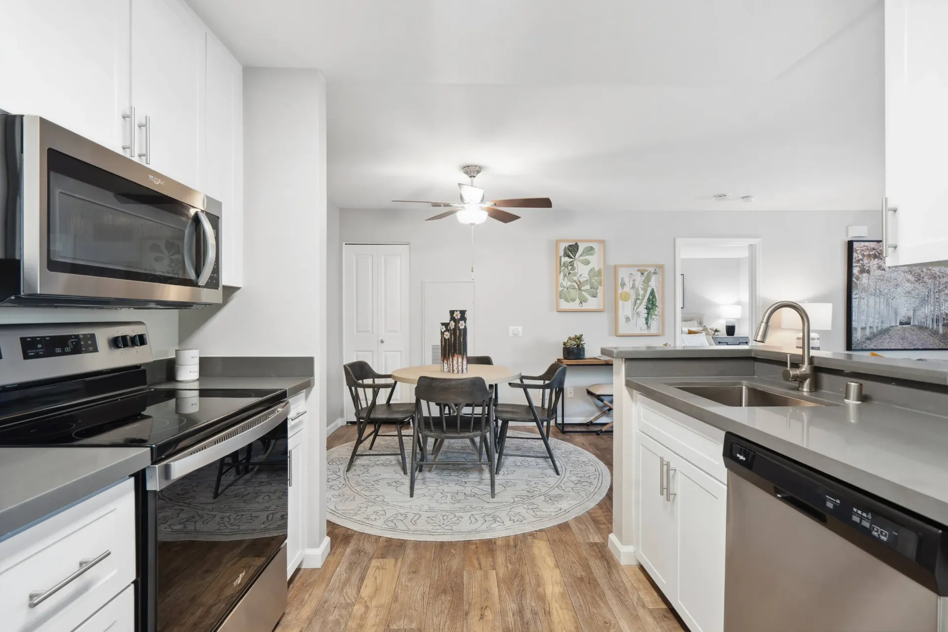Open-concept kitchen and dining area with stainless steel appliances and a round rug.