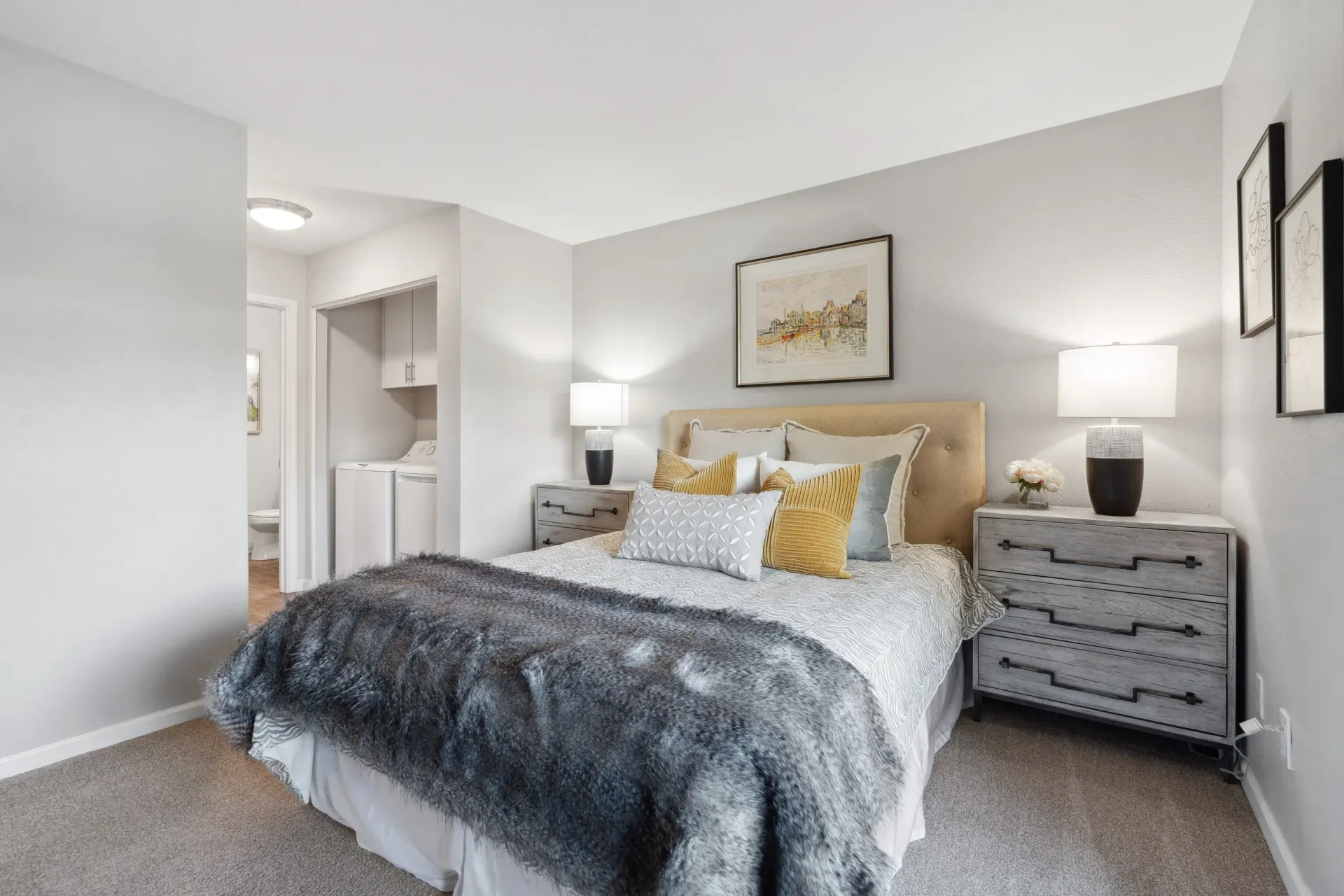 Cozy bedroom in a modern apartment with a tufted beige headboard, two gray nightstands, and a plush gray throw.