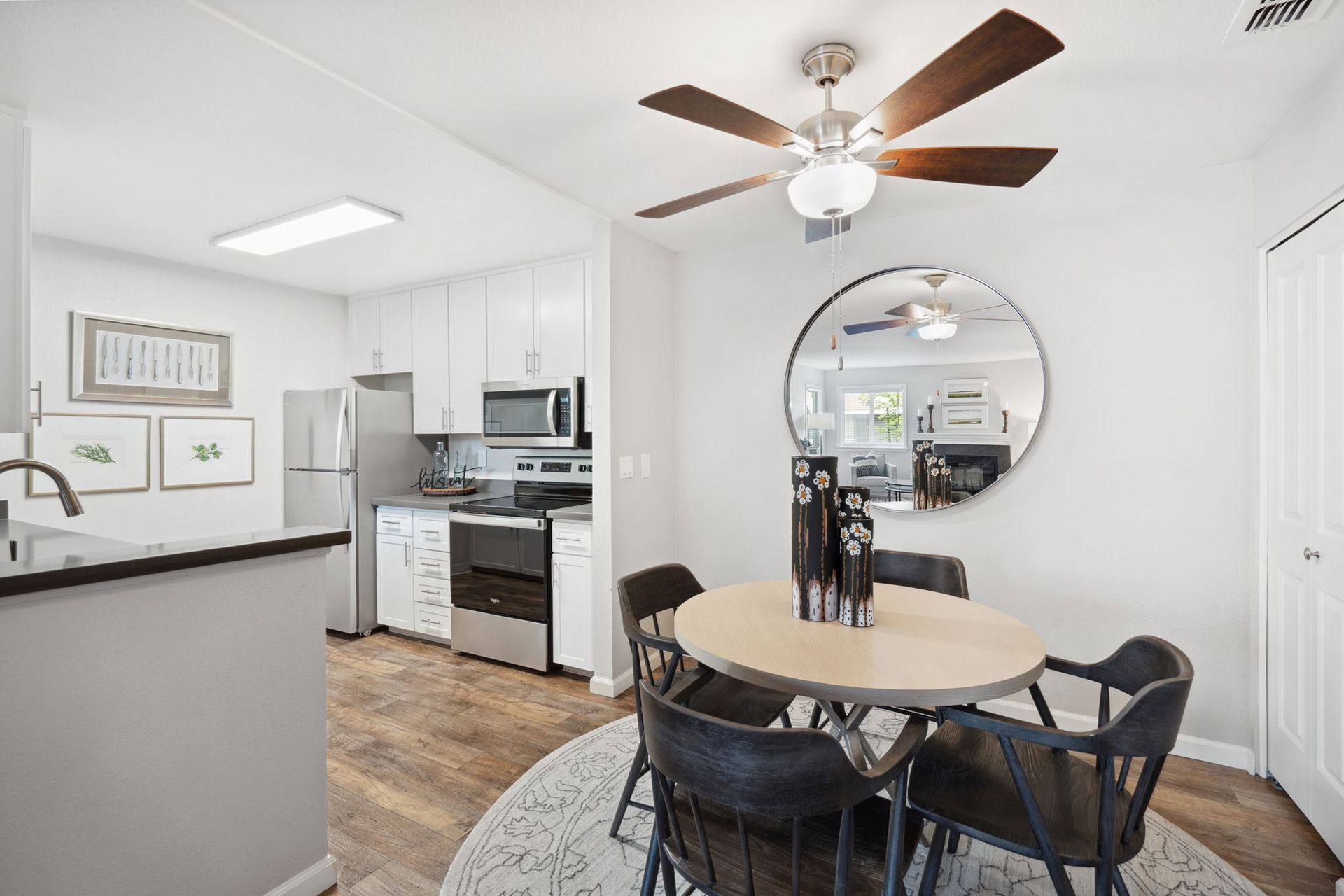 Bright kitchen and dining area in an apartment with white cabinets and stainless-steel appliances.