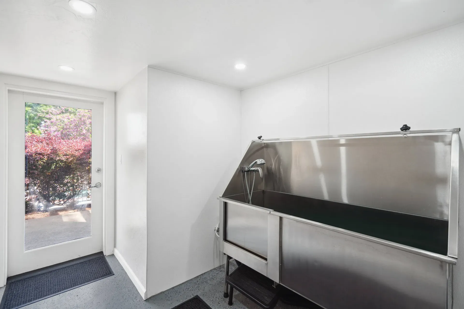 Bright utility room with a stainless steel laundry tub and door to outdoors.