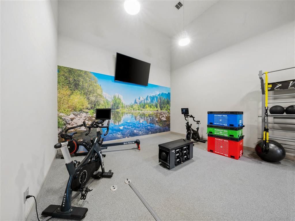 Indoor community gym with stationary bike, weights, and a wall mural.