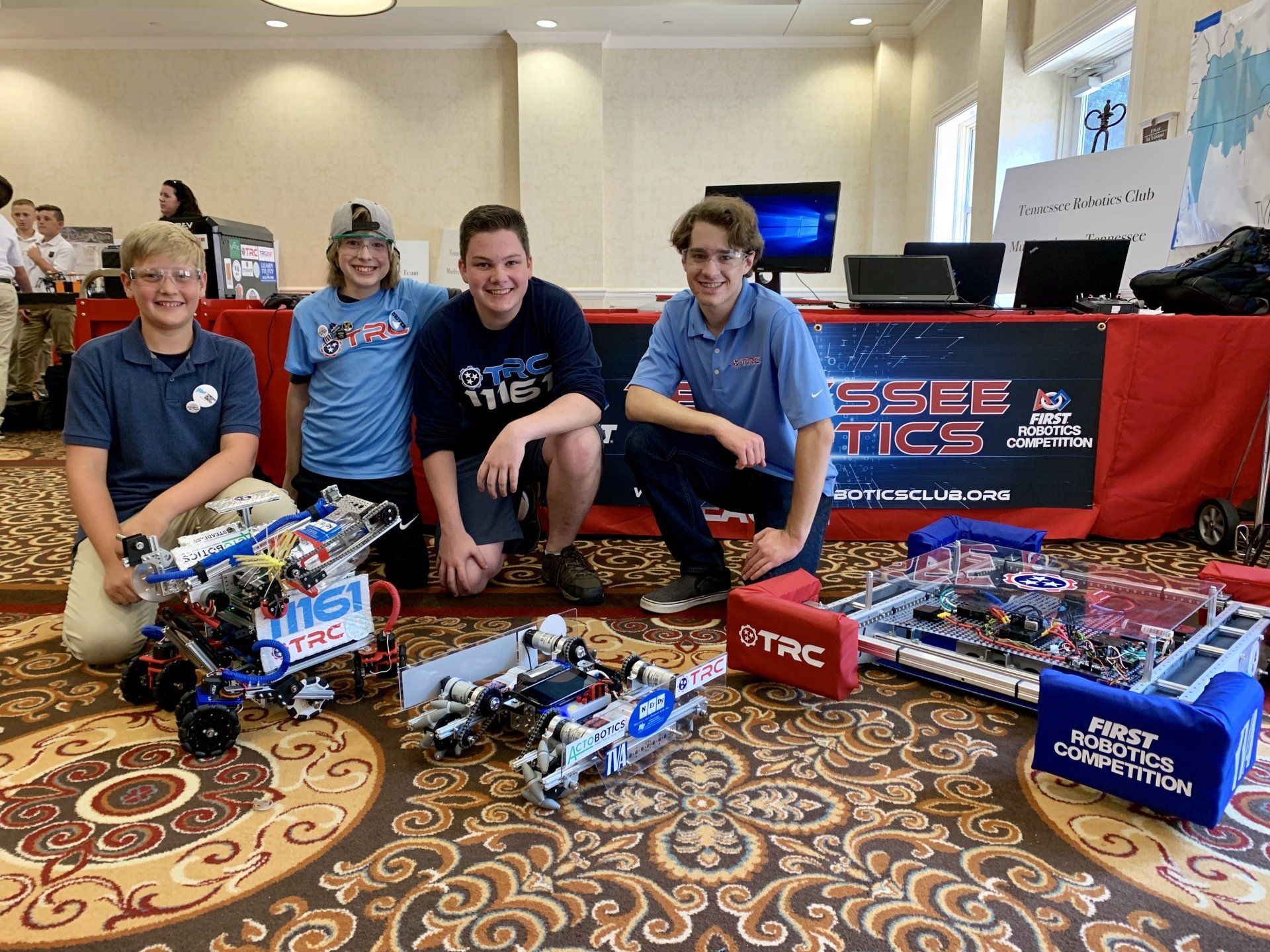 A group of young men are posing for a picture with their robots.