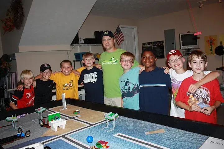 A group of kids are posing for a picture with a man in a nike shirt