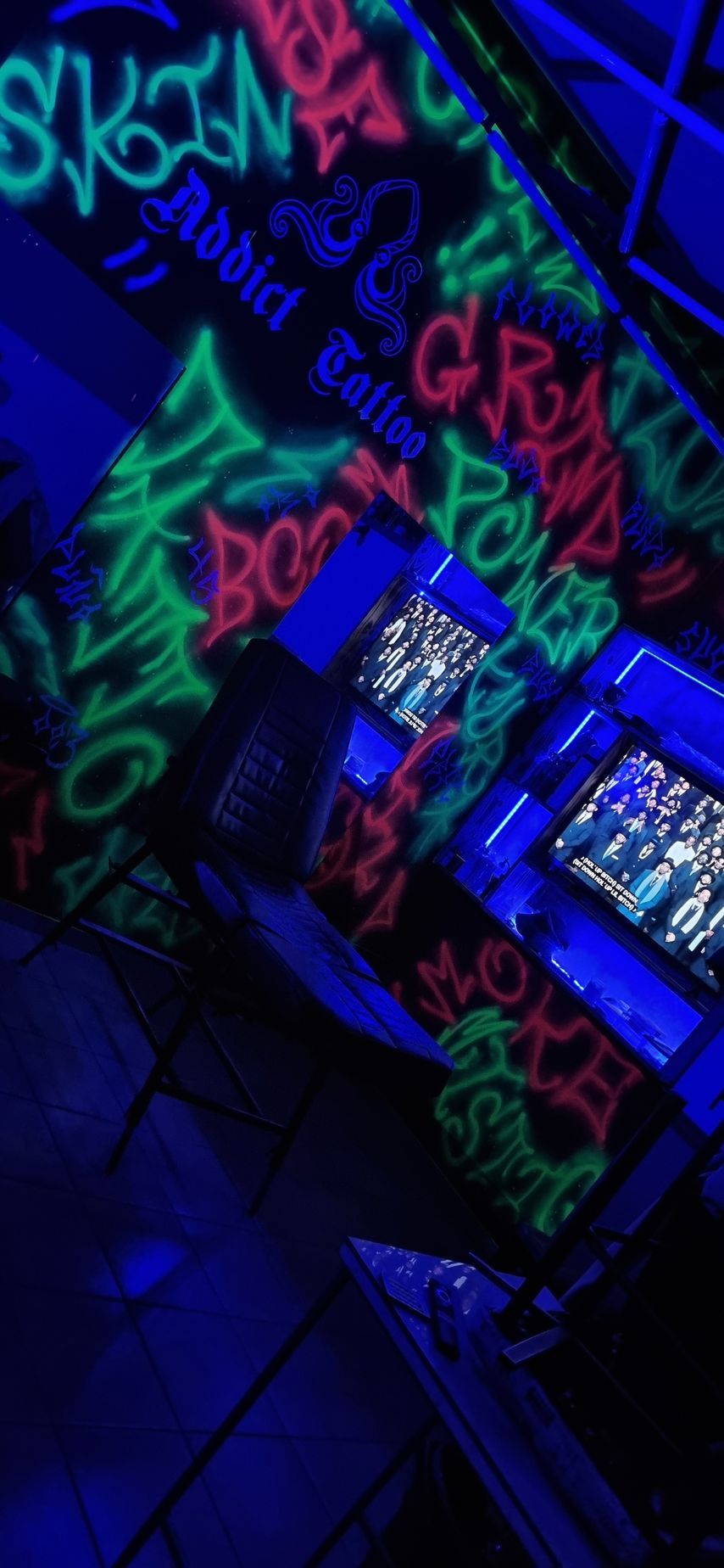 Arte de grafiti sobre una superficie iluminada en azul con texto verde neón y rosa, incluidas las palabras 