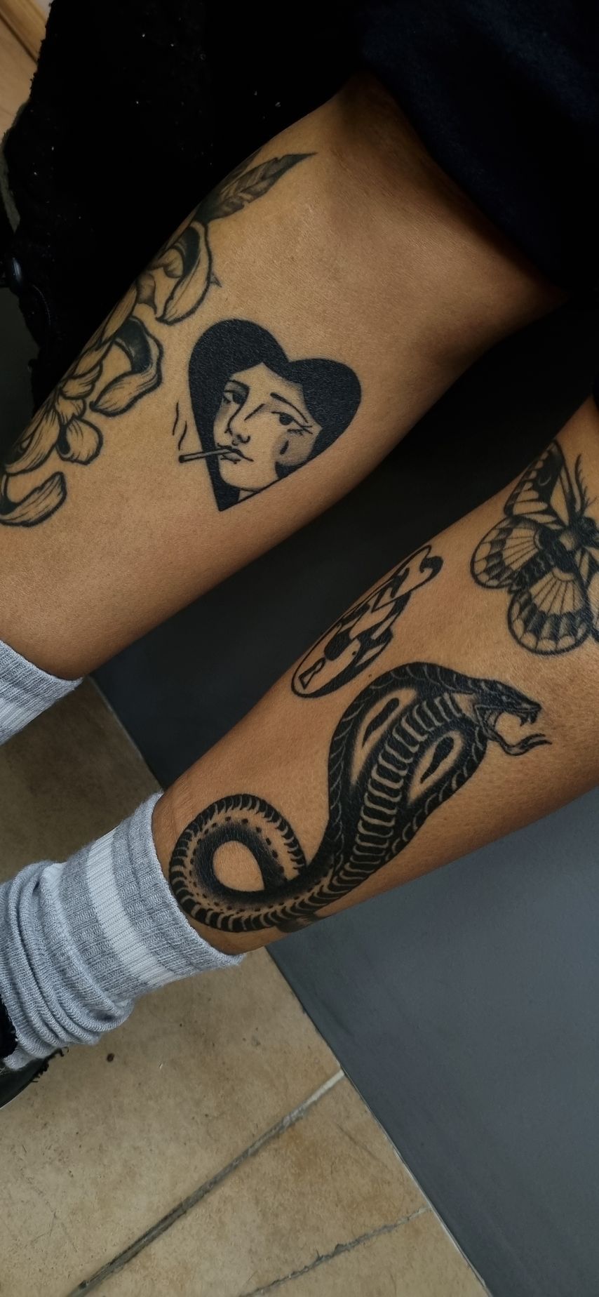 Brazos de una persona con varios tatuajes, entre ellos una serpiente, un corazón y otros diseños.