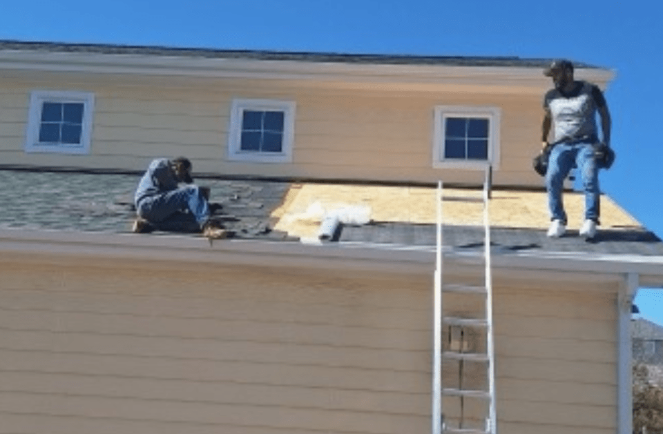 Two men are working on the roof of a house