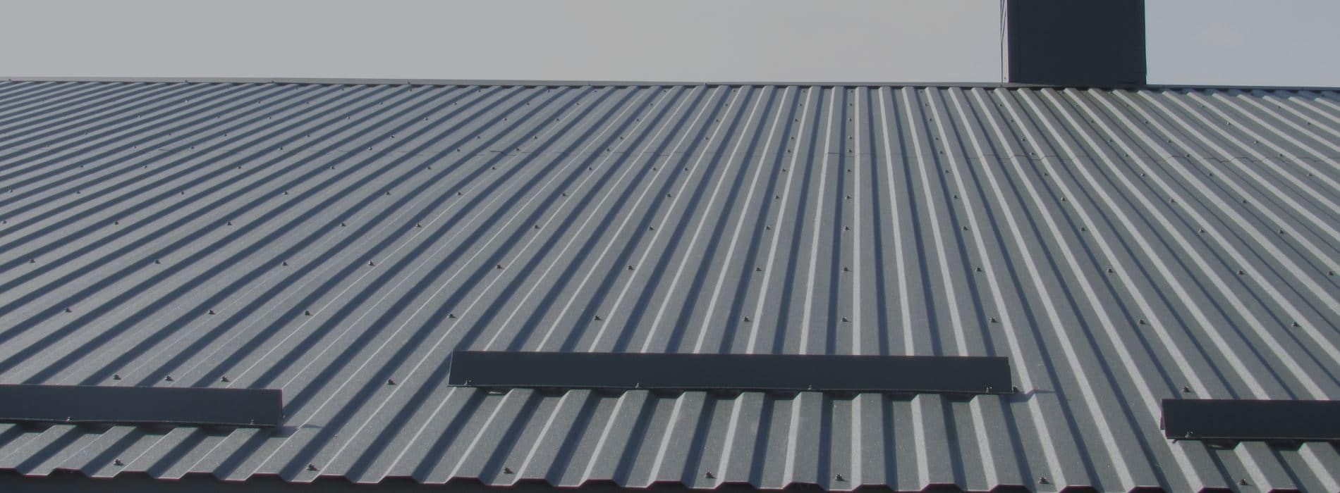 A close up of a metal roof with a chimney on top of it.