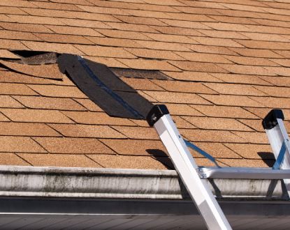A ladder is sitting on top of a roof with a hole in it.