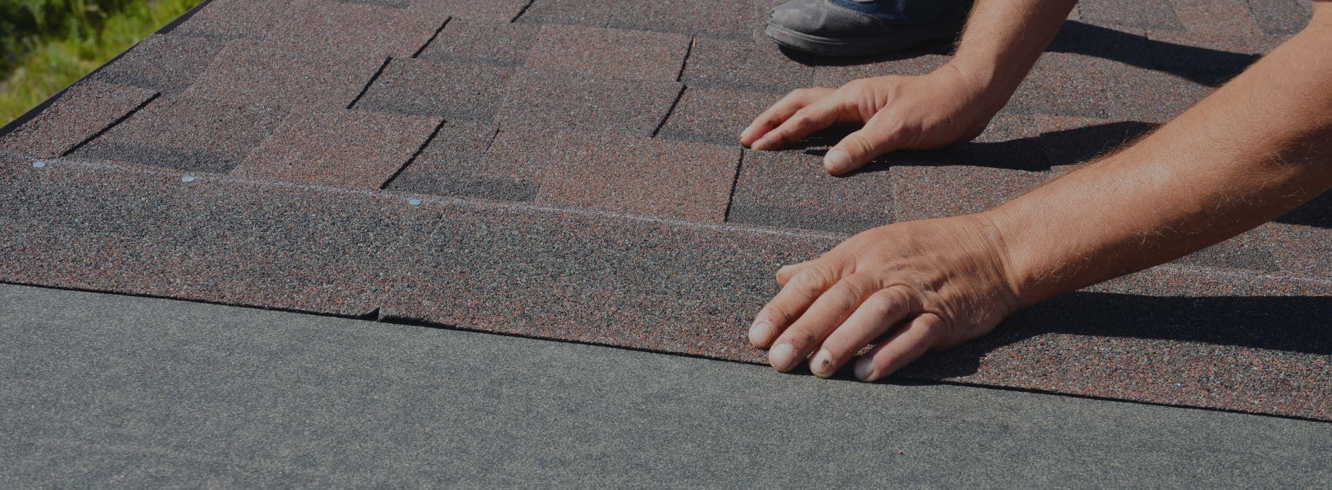 A person is laying shingles on a roof.