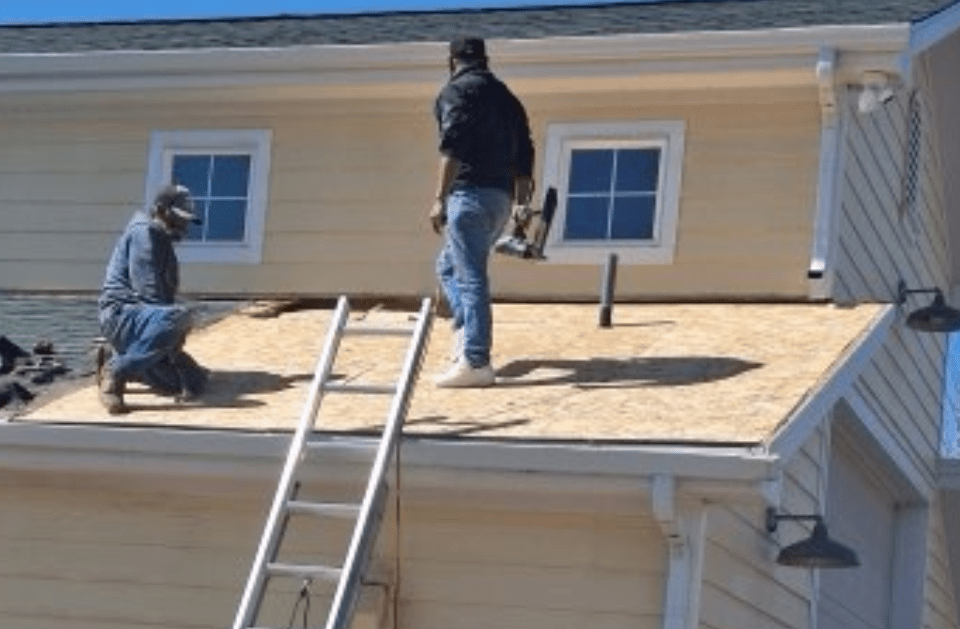 Two men are working on the roof of a house.
