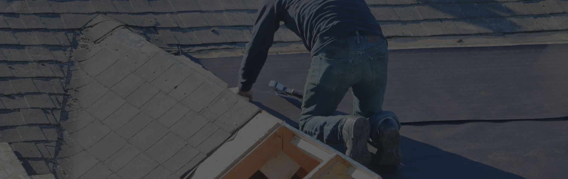 A man is standing on top of a roof holding a piece of wood.