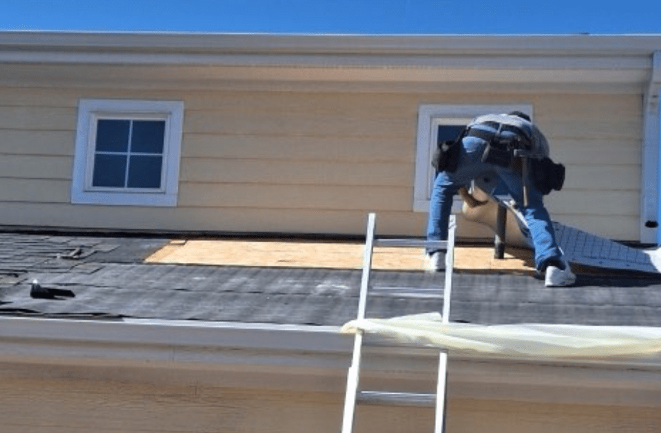 A man is working on the roof of a house with a ladder.