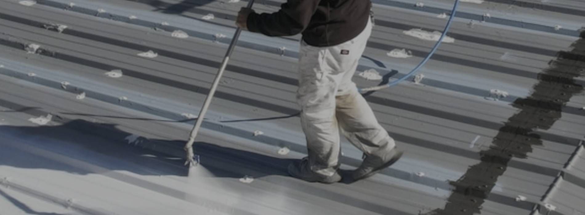 A man is spraying a roof with a sprayer.