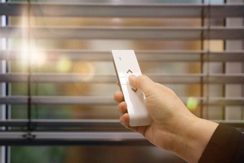 male hand holds a remote control to open the window blinds