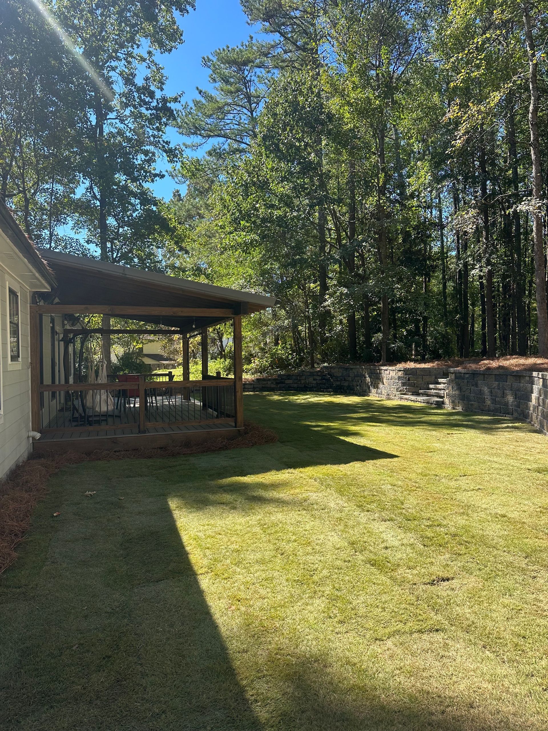 There is a gazebo in the backyard of a house surrounded by trees.