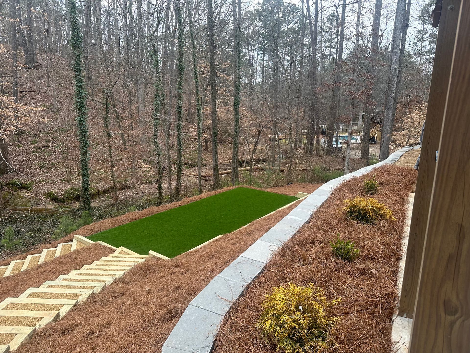 A staircase leading up to a grassy area with trees in the background.