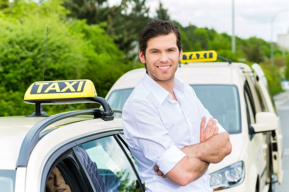Driver grinning while leaning on side of taxi
