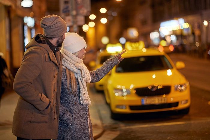 Couple in winter clothes hailing taxi