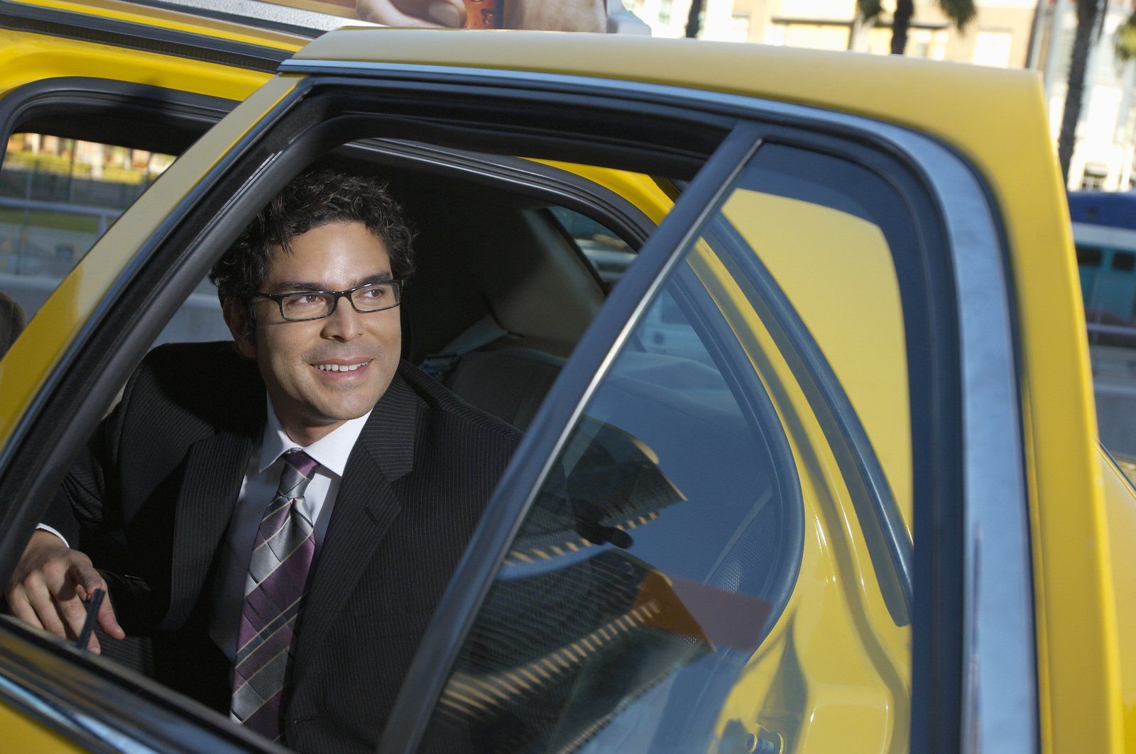 Man in suit exiting taxi while smiling