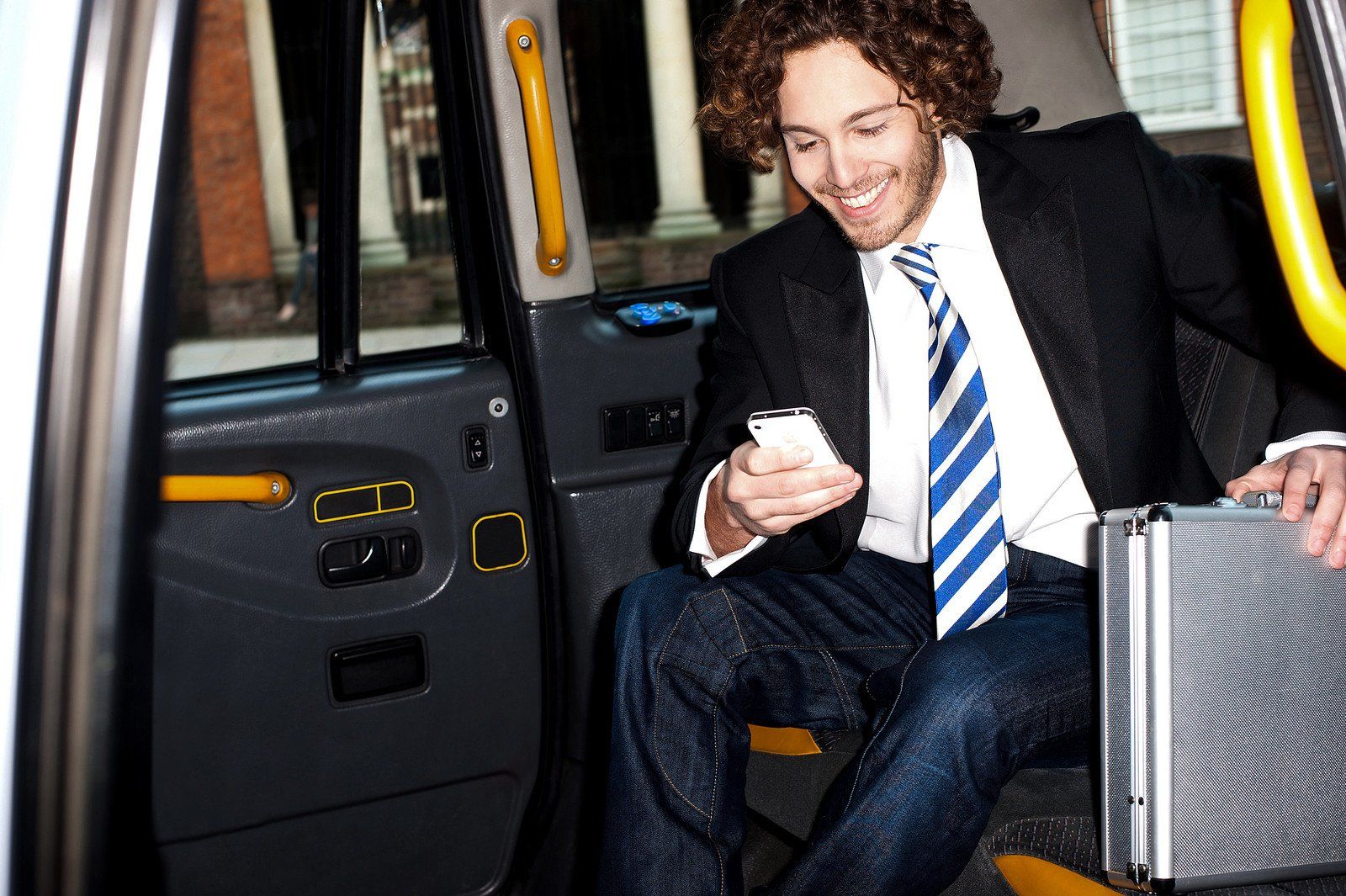 Young man in suit looking at cellphone while riding taxi.