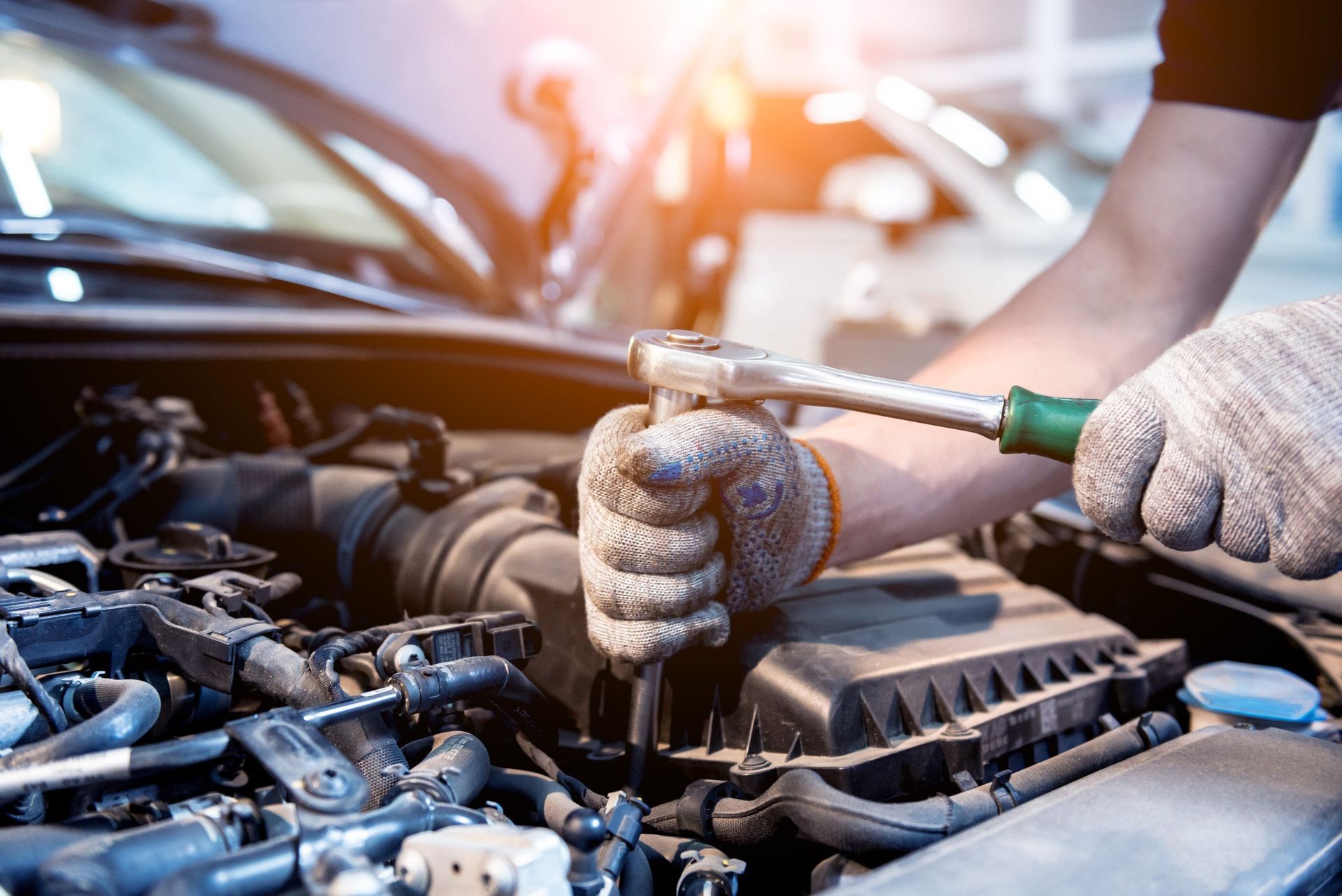 A man is working on the engine of a car with a wrench.