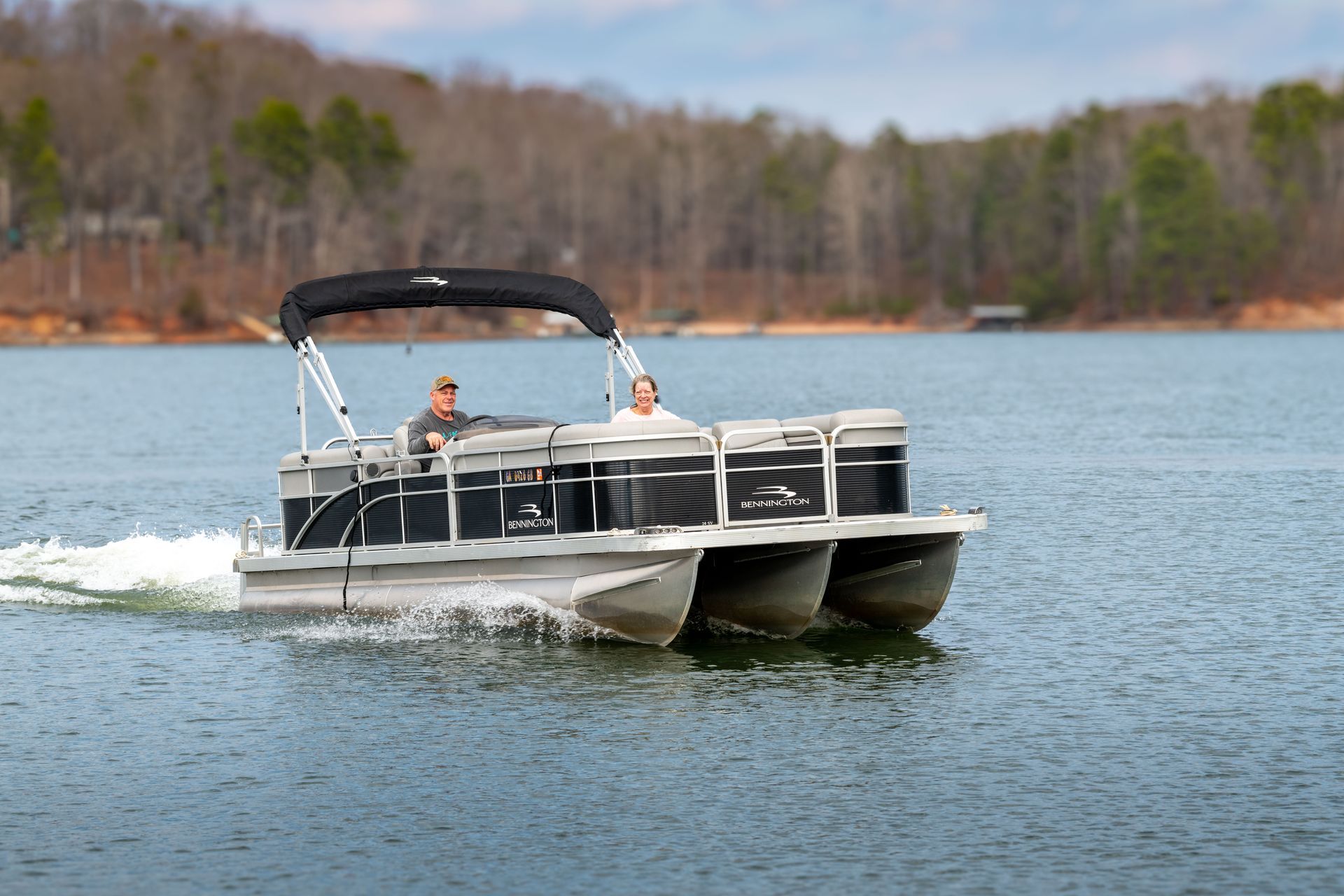 A pontoon boat is floating on top of a lake.