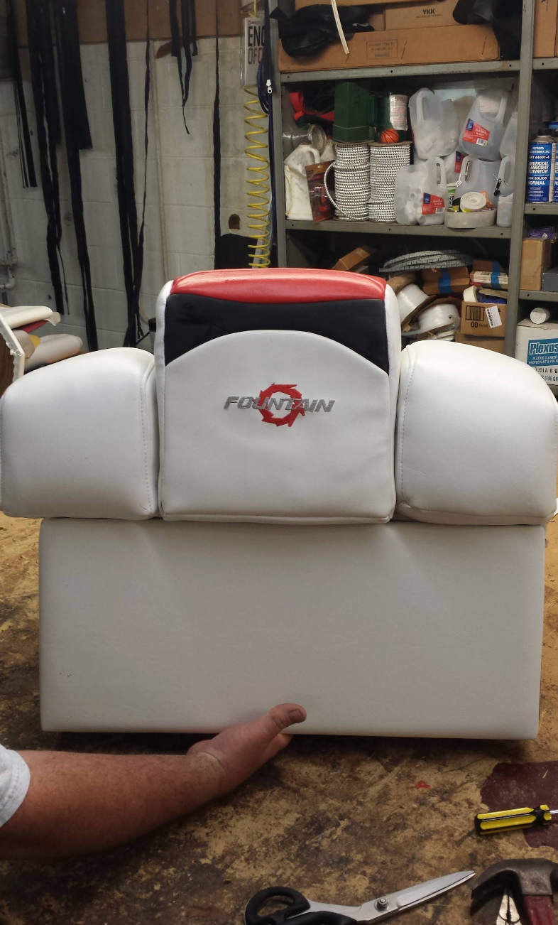 A person is working on a boat seat in a garage.