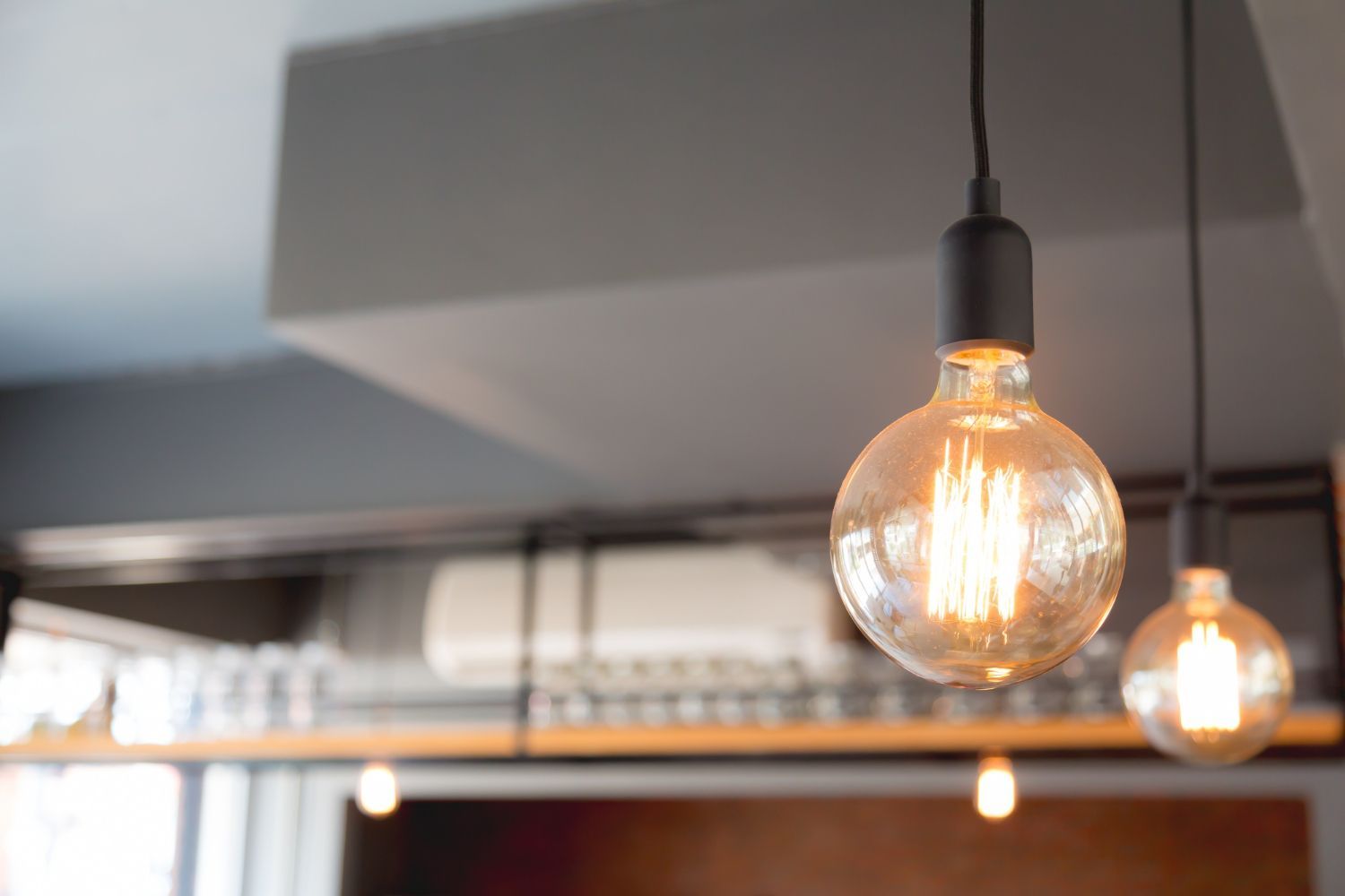 Two Edison-style light bulbs hang from a gray ceiling, illuminating a modern interior.
