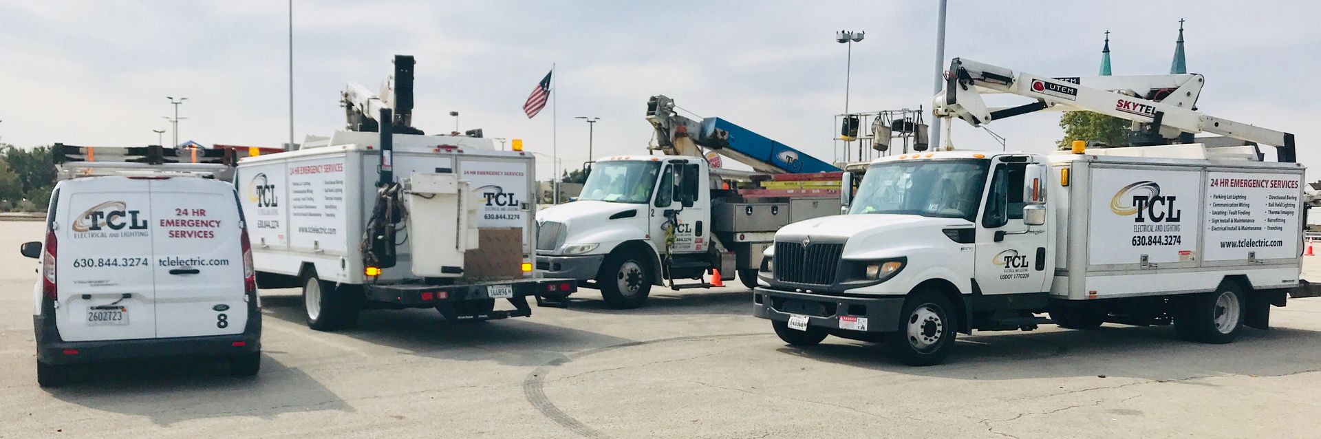 A fleet of white trucks with company logos parked in a lot. The trucks have lift equipment.