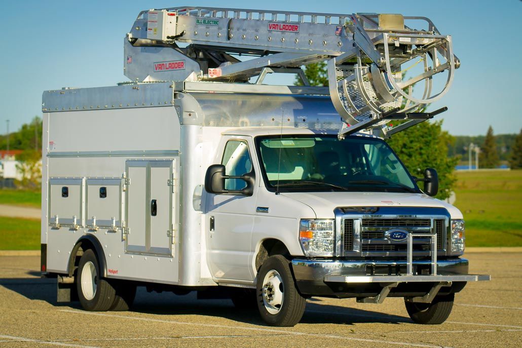 White utility truck with an aerial lift, parked outdoors.