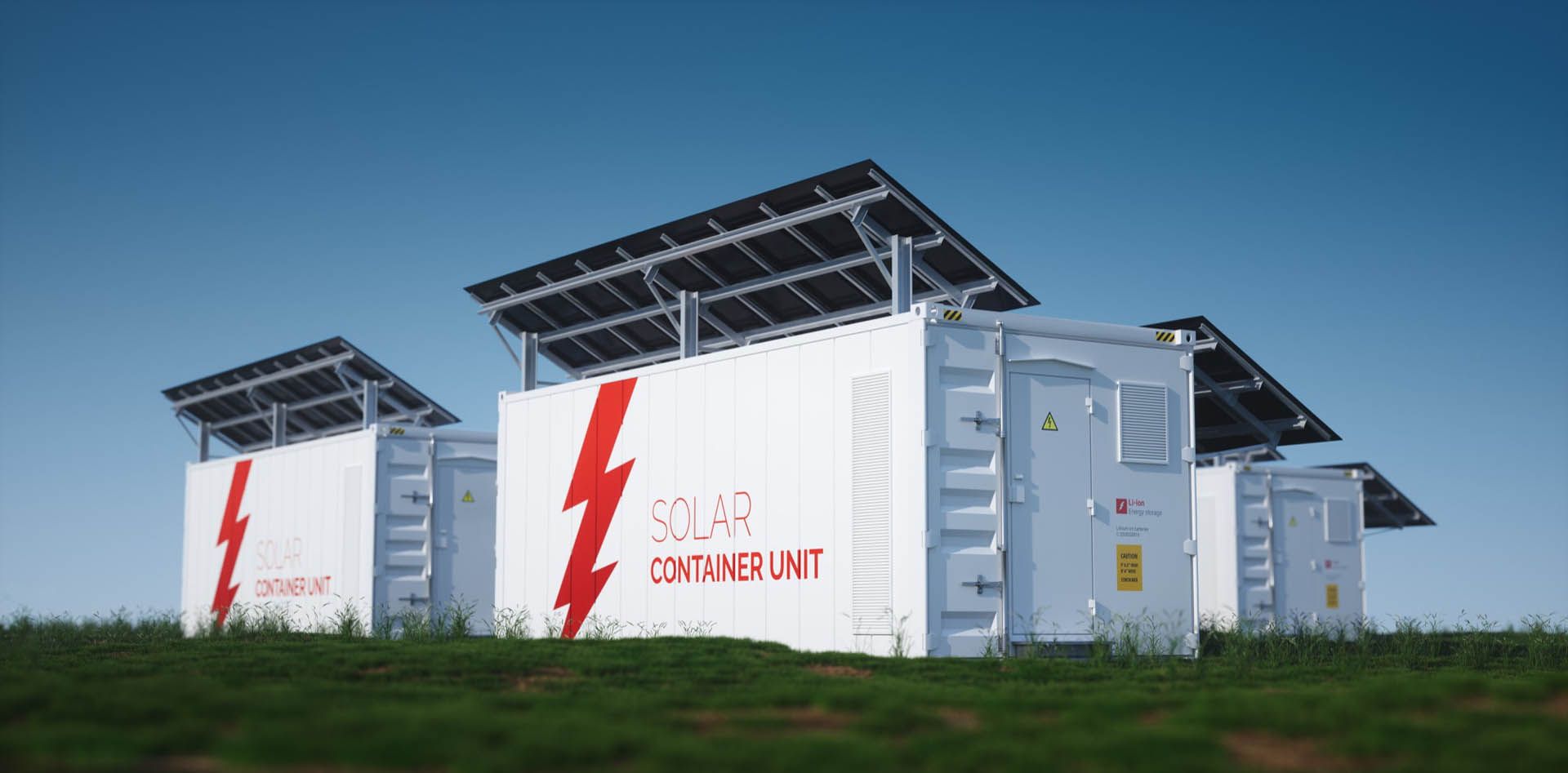 Solar container units with solar panels on a grassy hill against a clear blue sky.