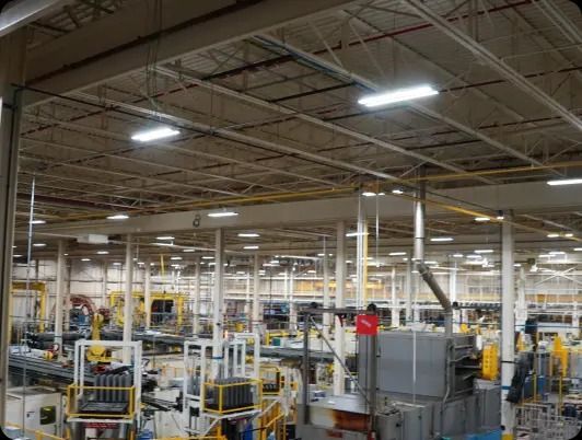 Factory interior with overhead lighting, machinery, and workers.