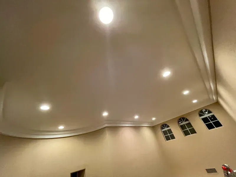 Beige-colored room interior with curved ceiling, recessed lighting, and arched windows.