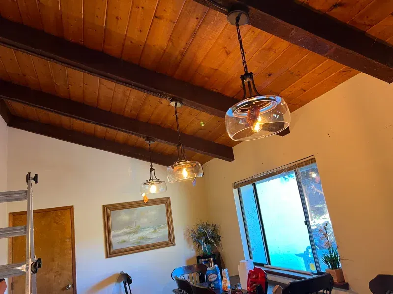 Wooden ceiling with hanging lights, a dining area, and a window with a blue view.