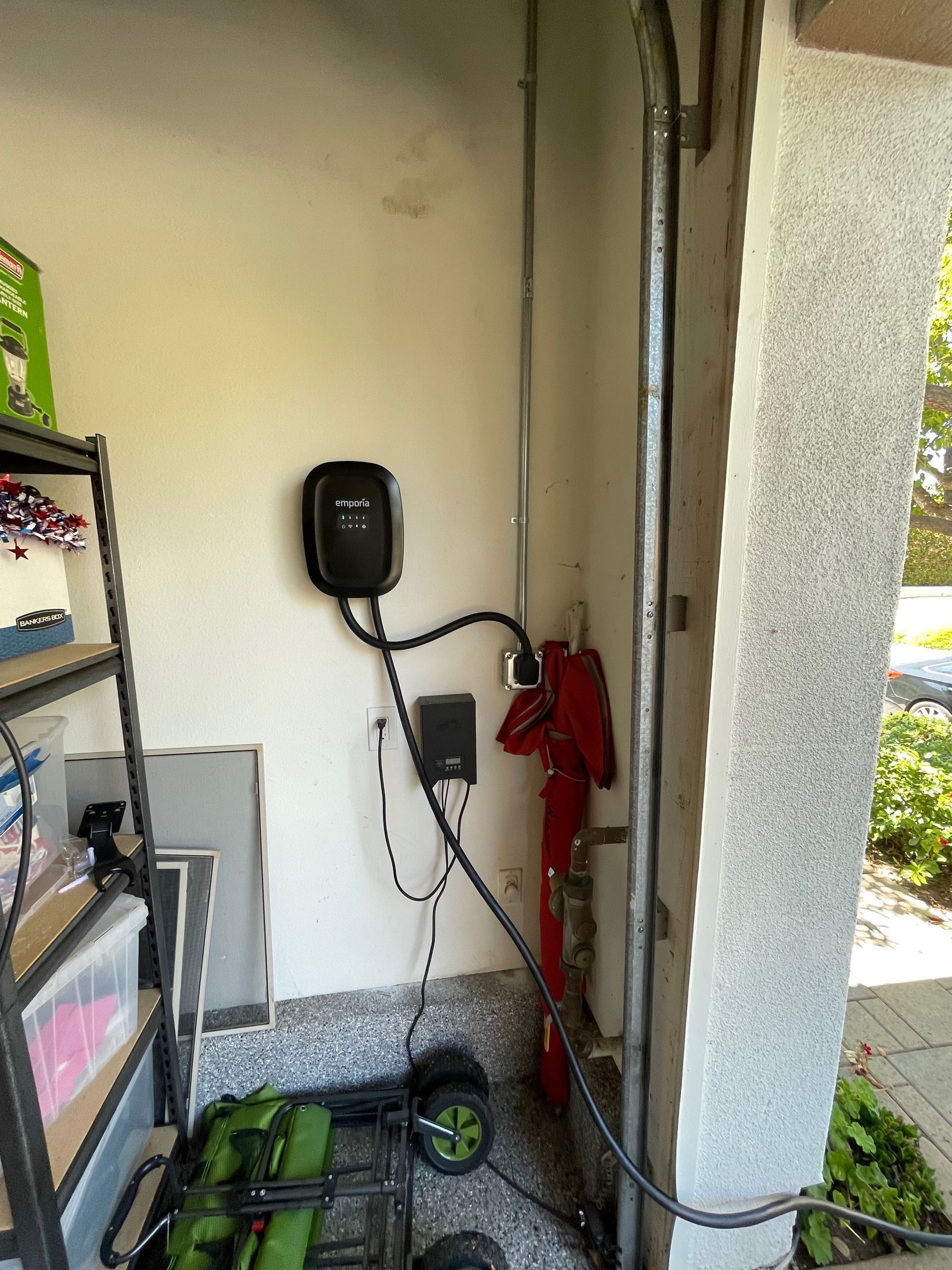 EV charger mounted on a garage wall with a connected car charging cable.