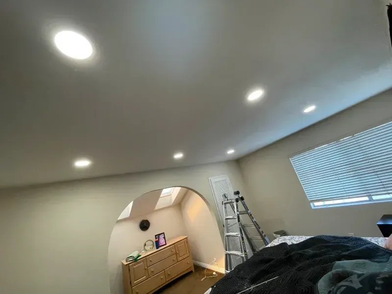 Bedroom with recessed ceiling lights, an arched doorway, a dresser, and a partially visible ladder.
