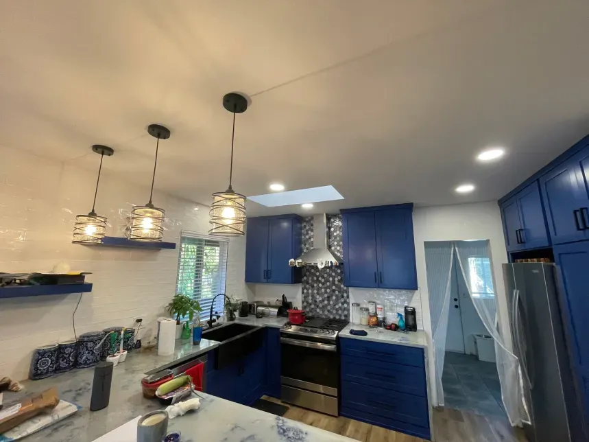 Kitchen ceiling with recessed lights, skylight, and blue cabinets.  Pendant lights hang over an island.