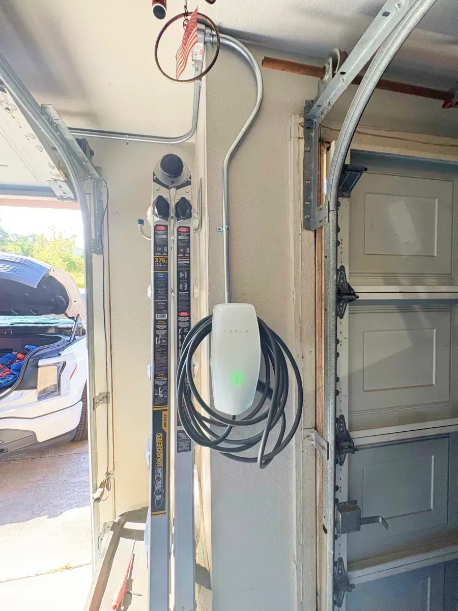 Electric vehicle charger installed in a garage, next to a garage door track and a lift.