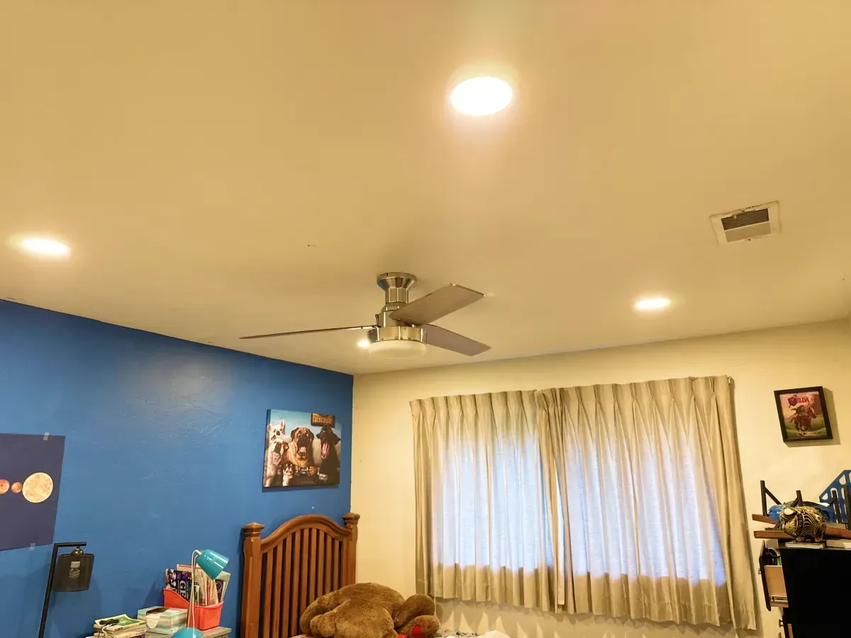 Bedroom with a ceiling fan, recessed lights, blue wall, wooden bed, curtains, and a photo.