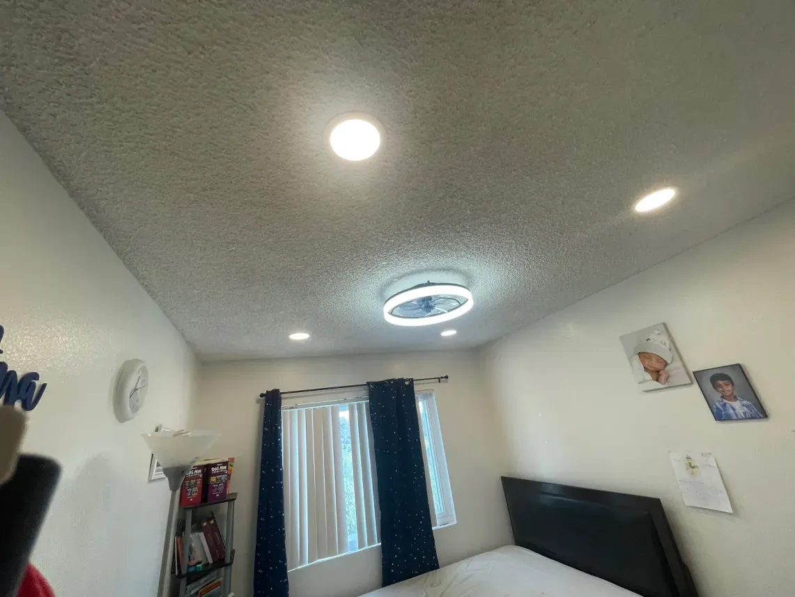 Bedroom with bed, curtained window, ceiling fan with light, and recessed lights.