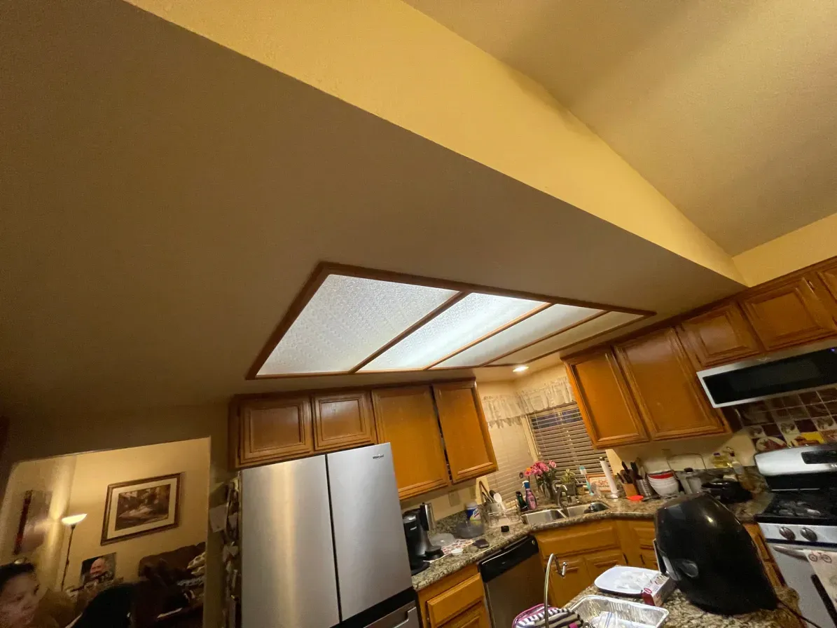 Kitchen with wooden cabinets, stainless steel refrigerator, and recessed lighting.