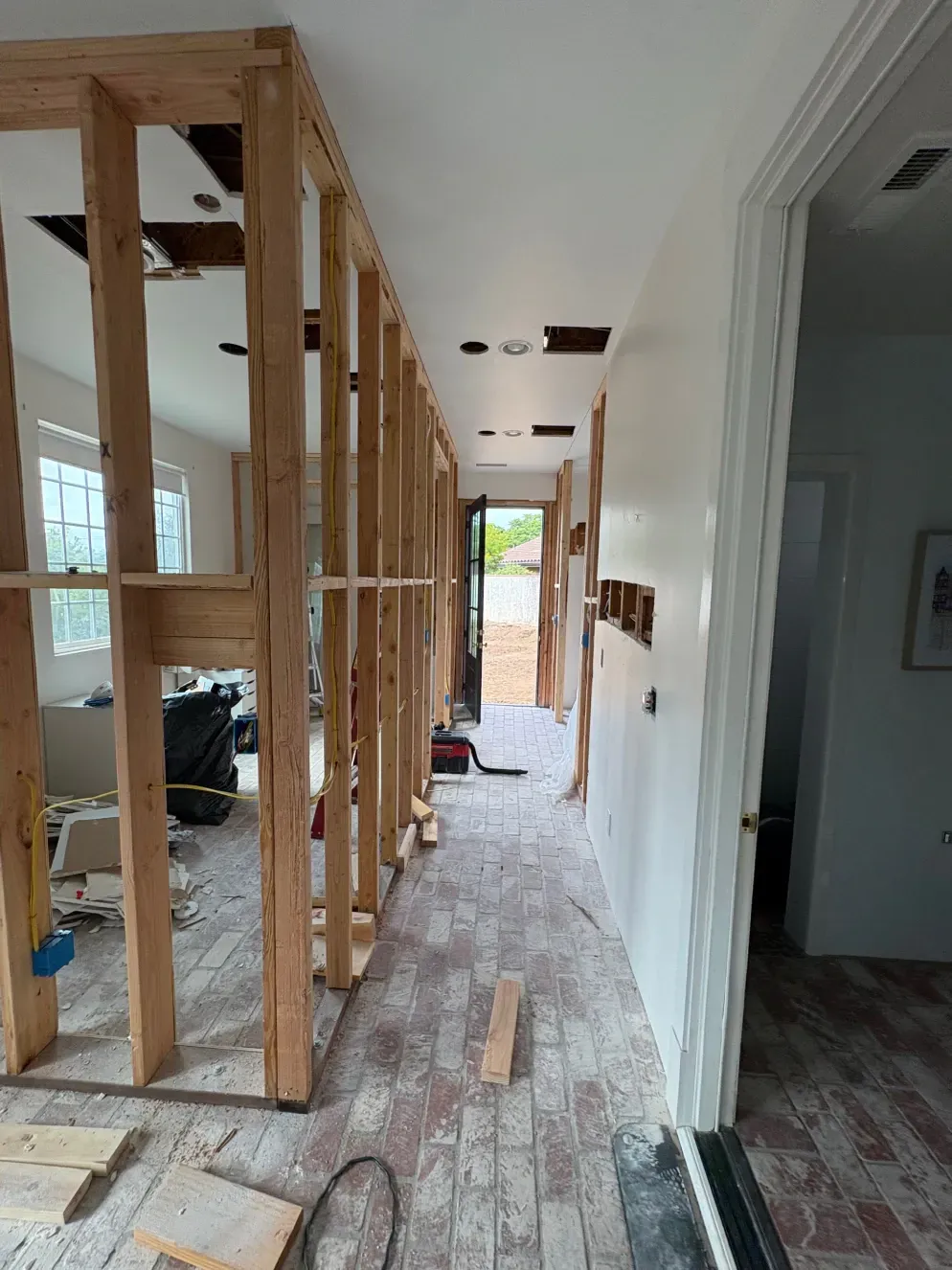 Hallway under construction with exposed wooden studs. Drywall removed from ceiling and wall.