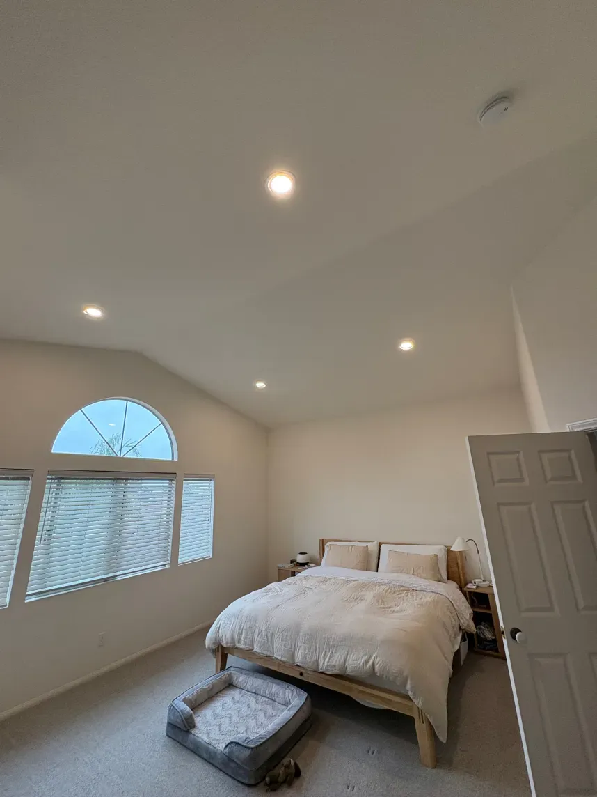Bedroom with bed, dog bed, arched window with blinds, and recessed lighting.