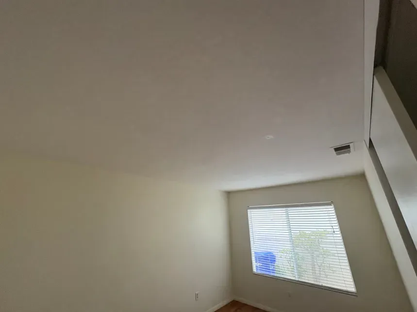 Interior view of a room with a window, white walls, and a sloped ceiling.