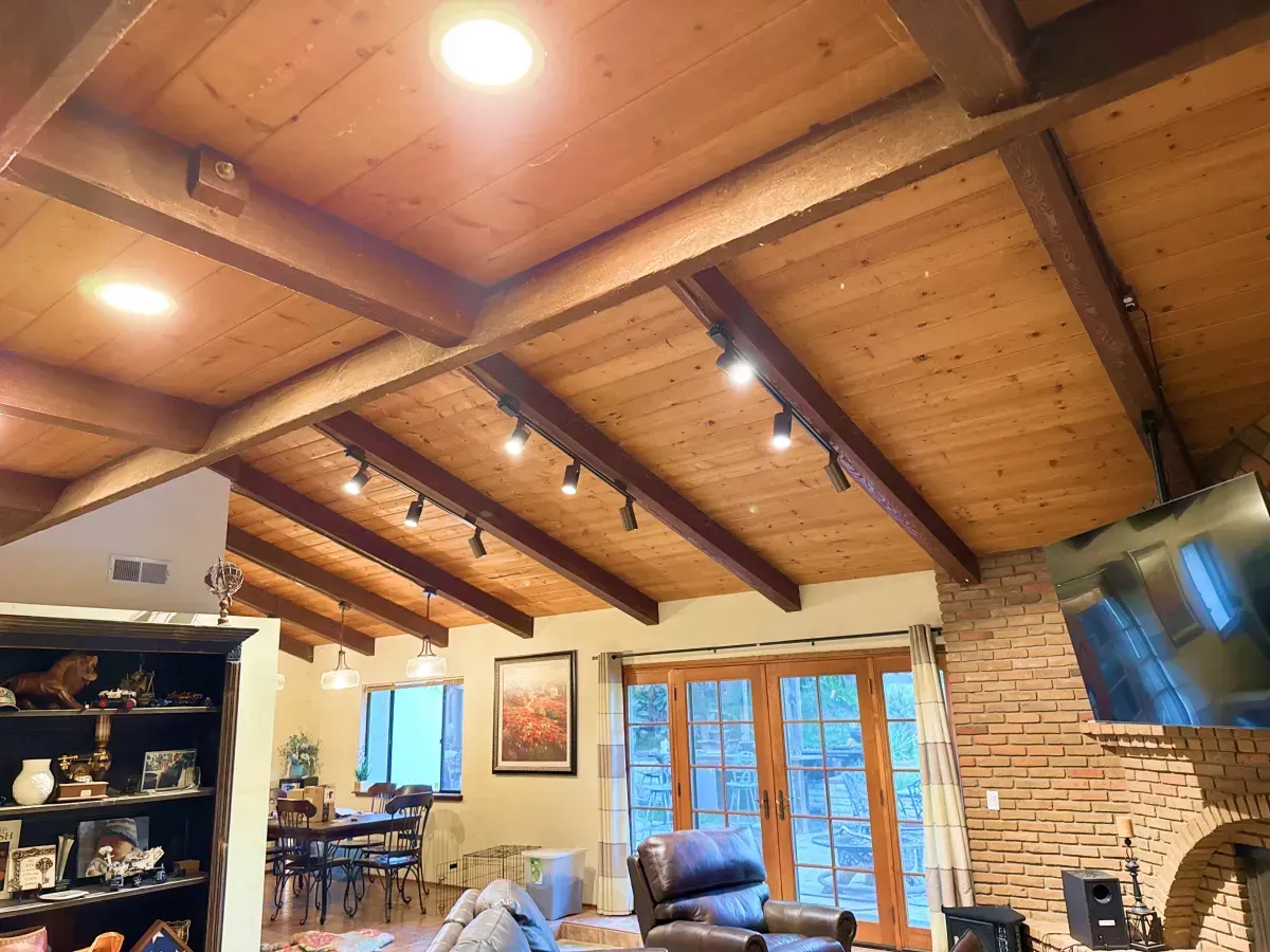 Wooden ceiling with beams and track lighting, living room with fireplace and french doors.