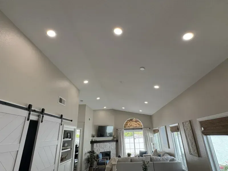 High-ceiling living room with recessed lighting, a fireplace, and white sliding barn doors.