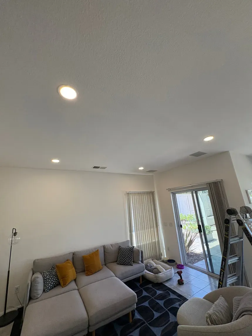 Living room with sectional sofa, recessed lighting, and sliding glass door.